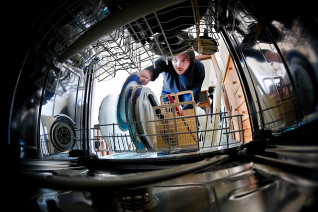 View of a man loading a dishwasher View of a man loading a dishwasher